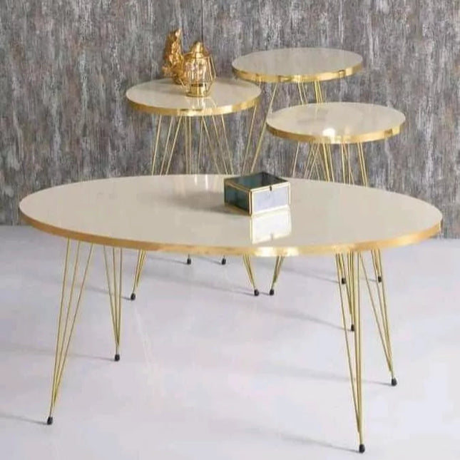 Set of three round tables with gold metal legs on a white floor against a gray textured wall.