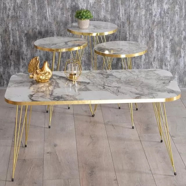 Set of marble tables with gold frames on a wooden floor against a gray stone wall.