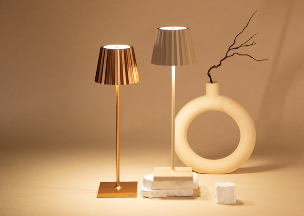 Two table lamps and a decorative vase on a beige surface with a neutral background